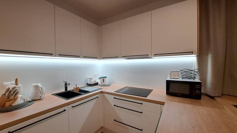 A kitchen in a 2-room apartment with wooden decor and cooking equipment.