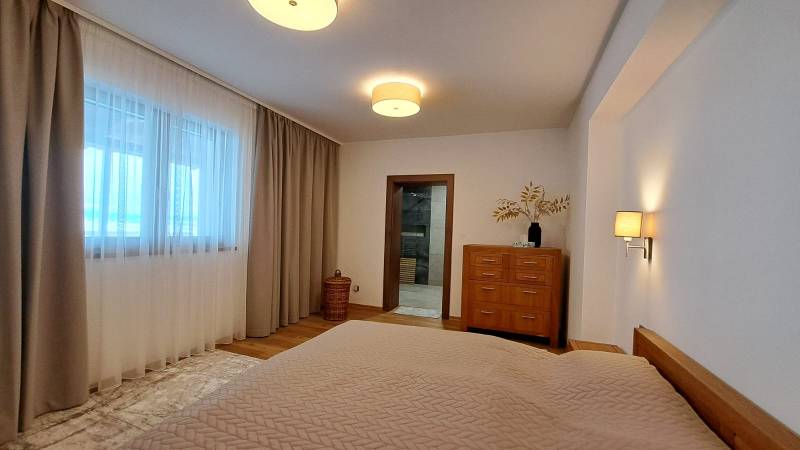 Bedroom in a 2-room apartment with wooden decor, curtains, and light furniture.