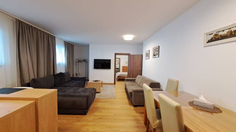 Living room with a sofa and TV, next to the dining table, floor with wood decor.