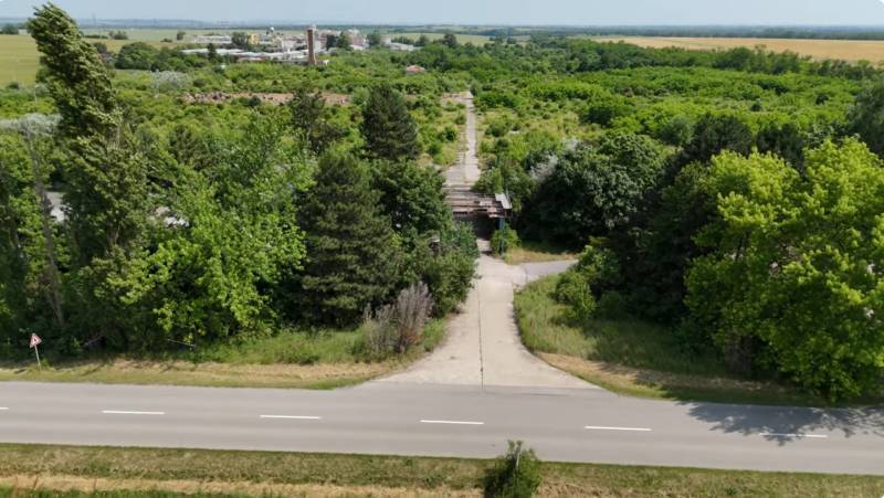 A path bordered by greenery offers a view of commercial land in Ivanka pri Nitre.