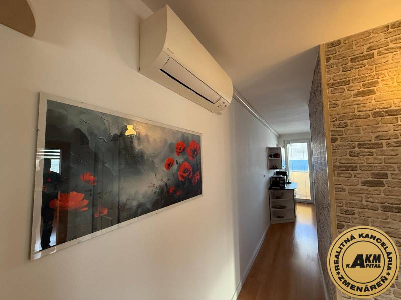 A hallway in a 3-room apartment with a wooden decor floor, a decorative brick wall, and air conditioning.