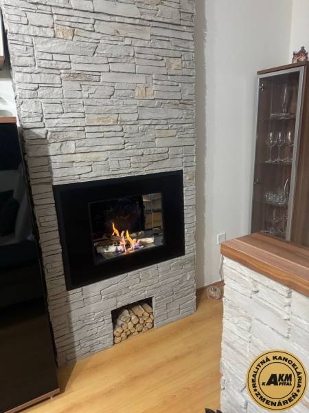 Fireplace with stone cladding, spacious room, floor with wooden decor, 3-room apartment.