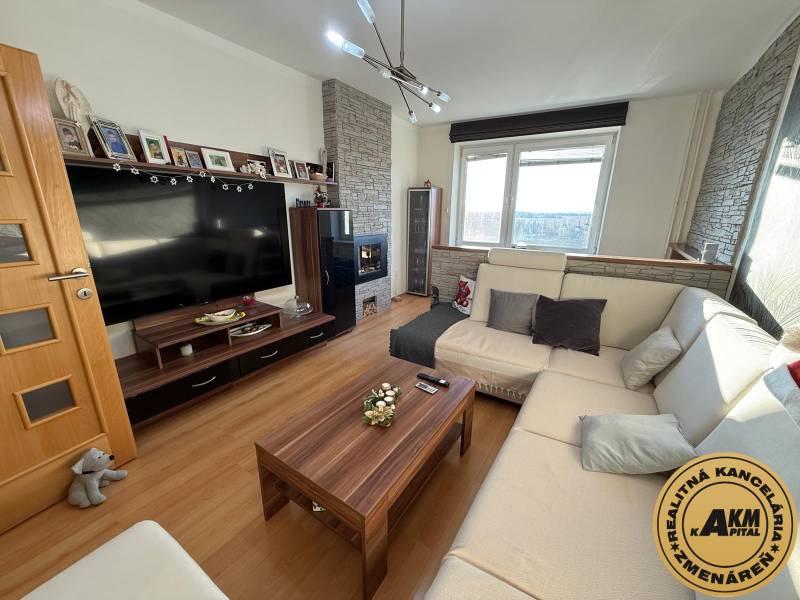 Living room in a 3-room apartment with a comfortable sofa, wooden decor flooring, and a television.