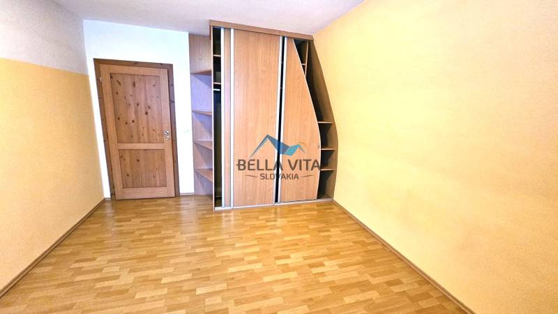 A room with a wooden decor floor, a built-in wardrobe, and wooden doors.