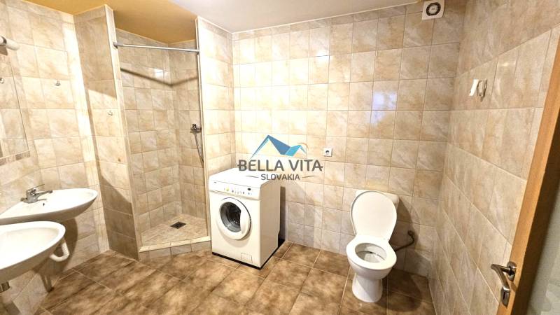 Bathroom with a washing machine, shower, and toilet. Walls with ceramic tiles and floor with decor.