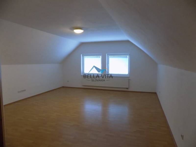 A white room with two windows and a wooden decor floor in a building.