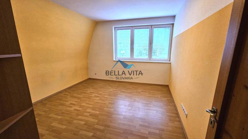 A room with a window, yellow walls, and a wood-patterned floor in a building.