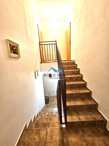 A staircase in a building with tiled cladding and railing, illuminated by white light.