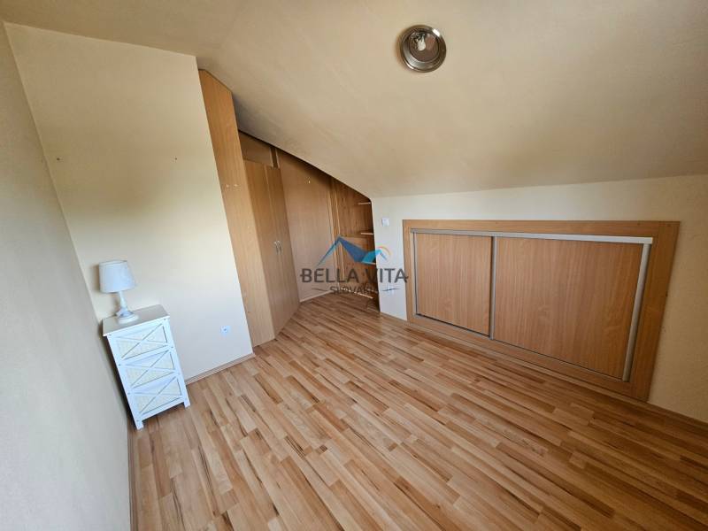A room with a wooden decor floor, a built-in wardrobe, and a nightstand.