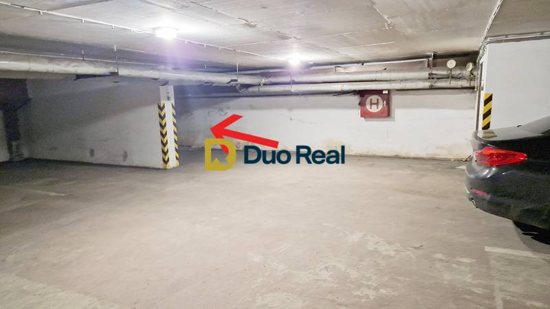 Underground parking area in the garage with a parking space by the wall and cars.