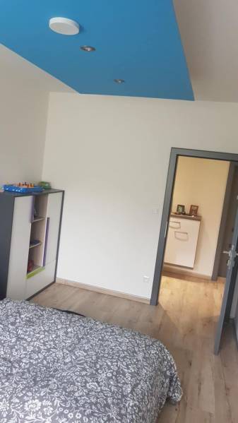 A room in a family house with a wooden decor floor and a blue ceiling.