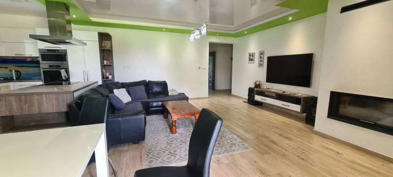 Living room in a family house with a leather sofa, television, and wooden decor flooring.