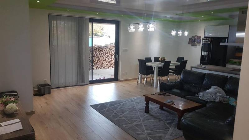 Living room in a family house with a wooden decor floor, sofa, and dining table.