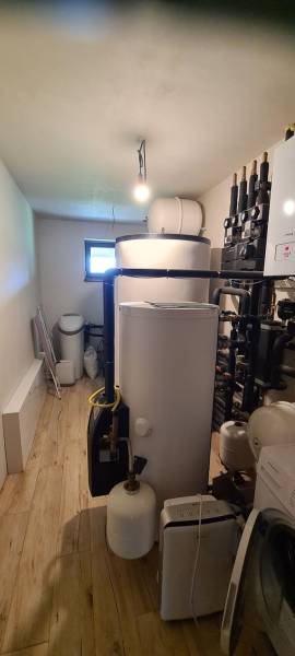 Technical room in a family house with a boiler, tanks, and a floor with a wooden decor.