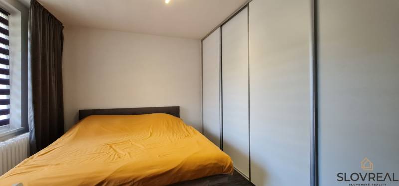 A bedroom in a 2-room apartment with white wardrobes and a yellow duvet.