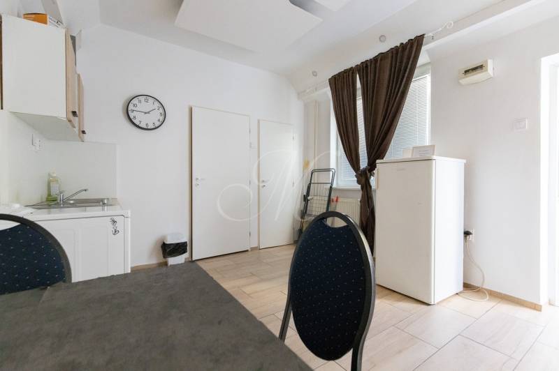 A kitchen in a one-room apartment with simple furnishings, floor with wood decor.