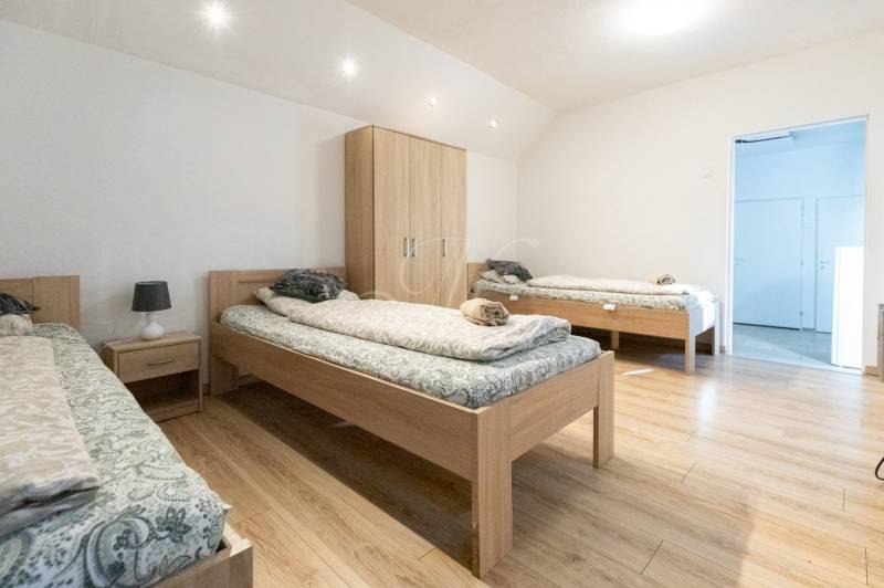 A bedroom with three beds, a wardrobe, and a wooden decor floor in a studio apartment.