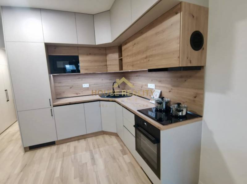 A kitchen in a studio apartment with a wooden decor floor and modern appliances.