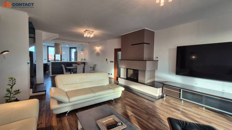 A spacious living room with a fireplace in a family house, light furniture, and a floor with a wood decor.