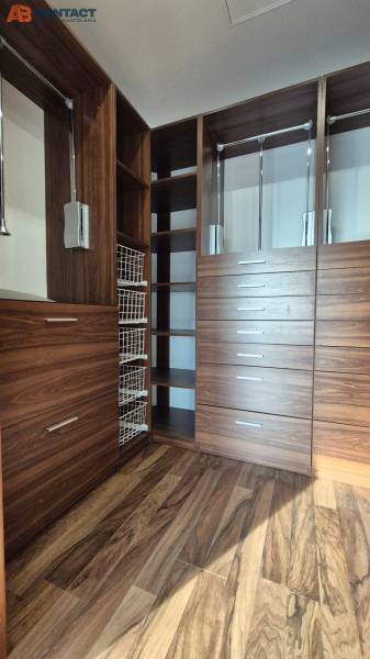 A wardrobe in a family house with a wooden decor and built-in storage systems.