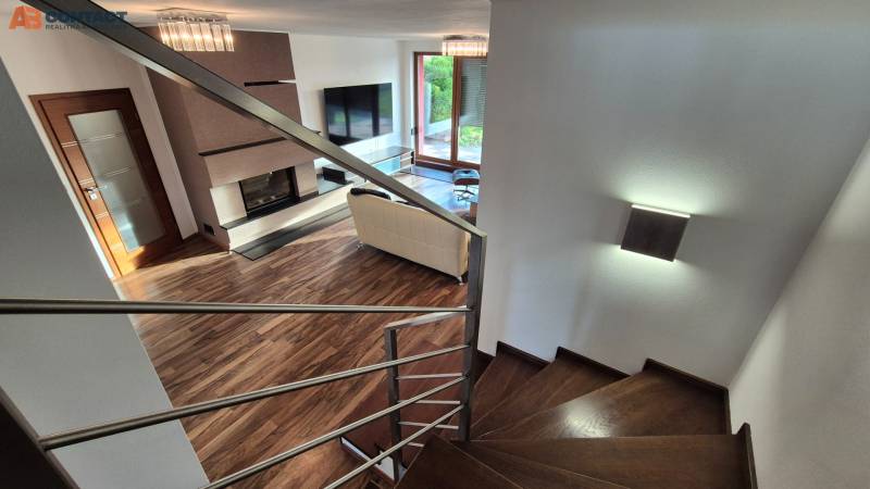 Living room with a fireplace and staircase in a family house, floor with wooden decor.