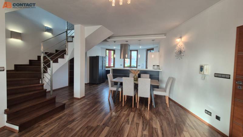 Interior of a family house with a kitchen, dining room, and staircase on a floor with a wooden decor.