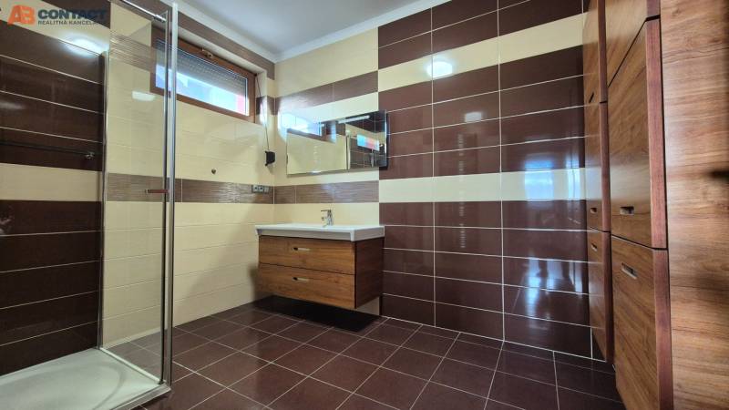 A bathroom with brown and cream tiles, a shower, and a sink, Family house.