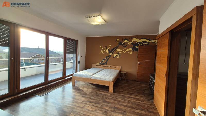 A room in a family house with a wooden decor floor, a double bed, and a terrace.