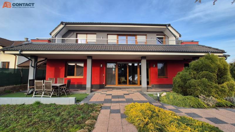 A family house in Krakovany on Vetrná Street, with a red facade and a garden.
