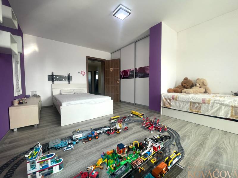 Children's room in a family house with a bed, toys, and a wooden decor floor.