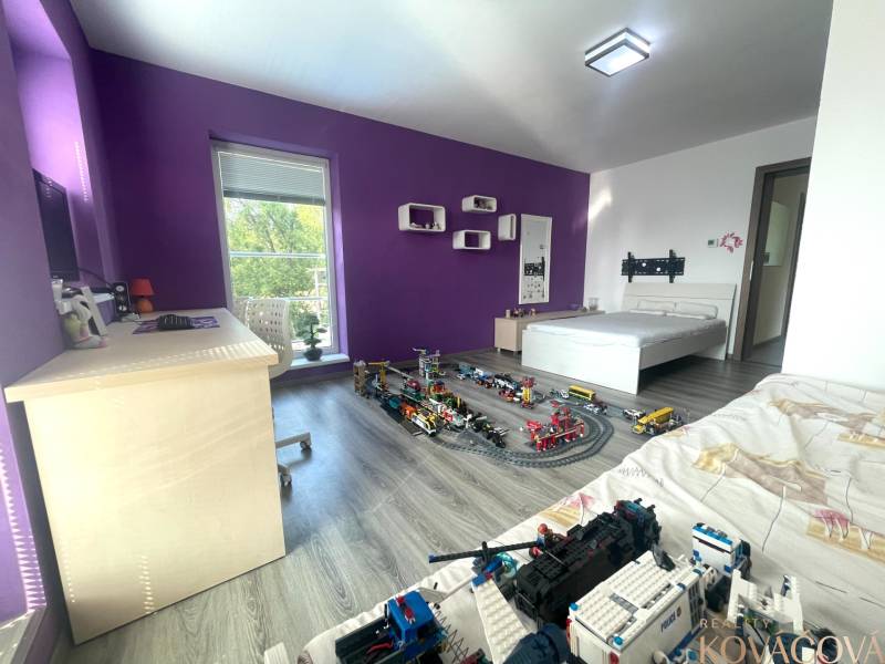 Children's room in a family house with purple walls, toys, and a wooden decor floor.