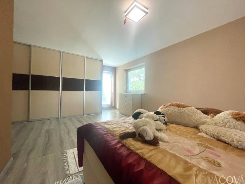 A bedroom in a family house with a wood-patterned floor, a built-in wardrobe, and plush toys.