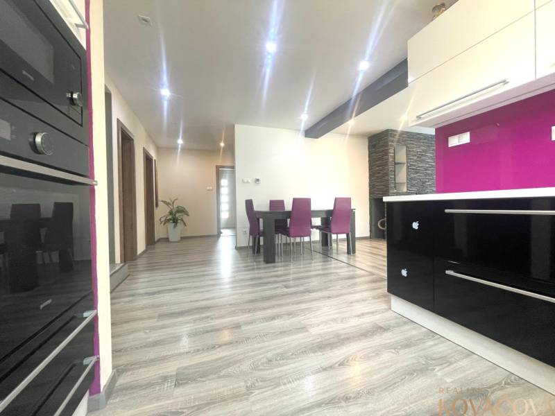 A kitchen in a family house with a wooden decor floor and purple chairs.