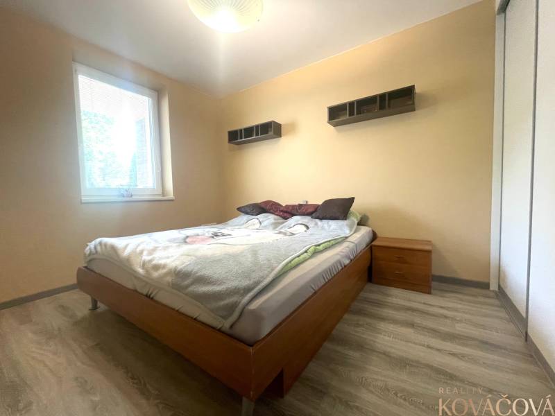 Bedroom in a family house with a bed, nightstand, and floor with wooden decor.