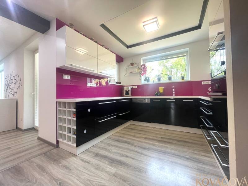 A kitchen with burgundy elements and a wooden decor floor in a family house.