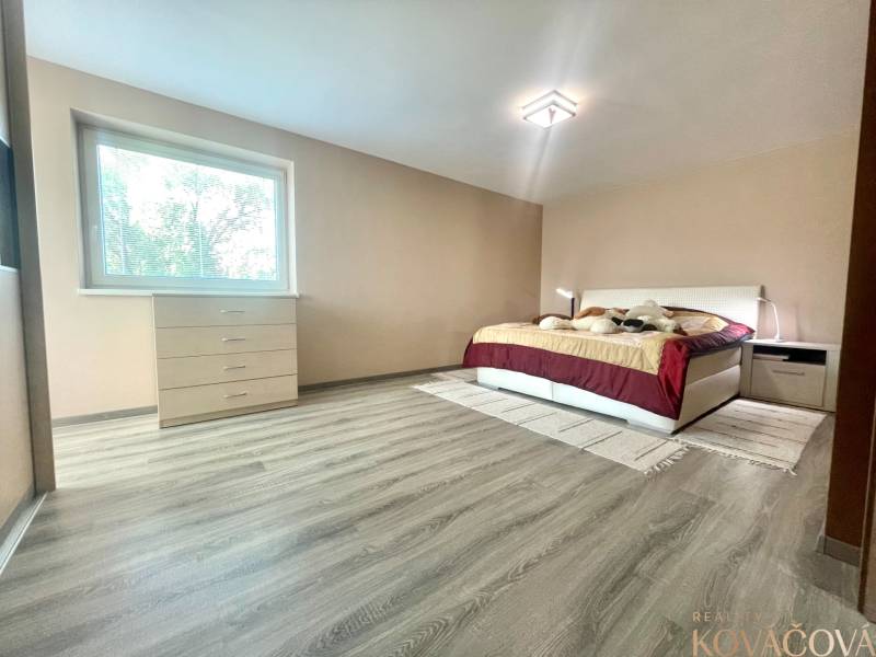 Bedroom in a family house with a bed, dresser, and wooden decor flooring.
