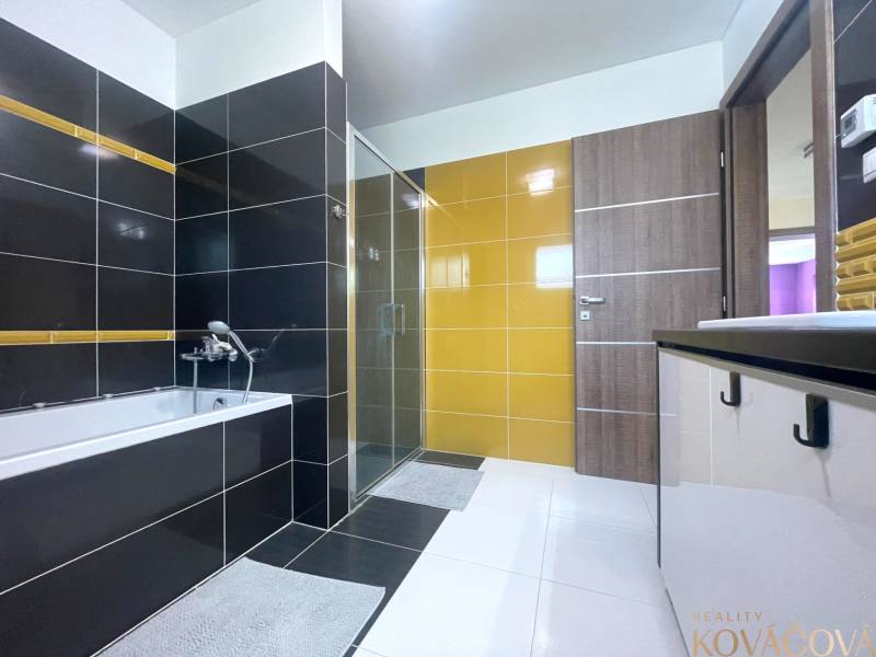A bathroom in a family house with a bathtub, a shower, and colorful tiles.