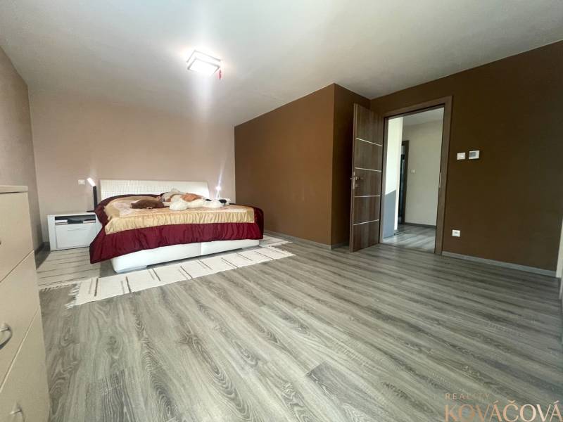 Bedroom in a family house with a bed, cabinet, and floor with wooden decor.
