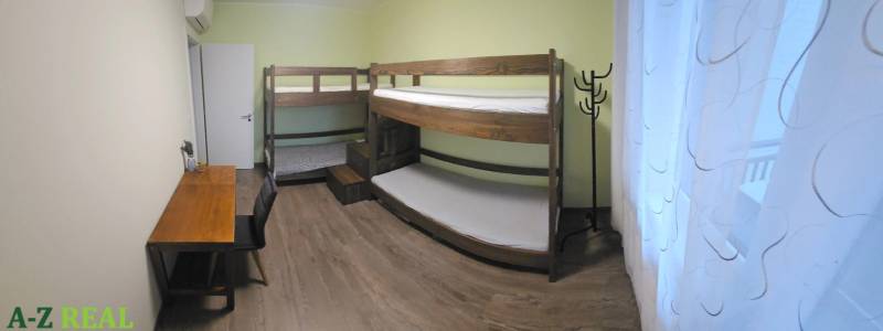 A room in a 3-room apartment with a bunk bed, a desk, and a floor with a wooden decor.