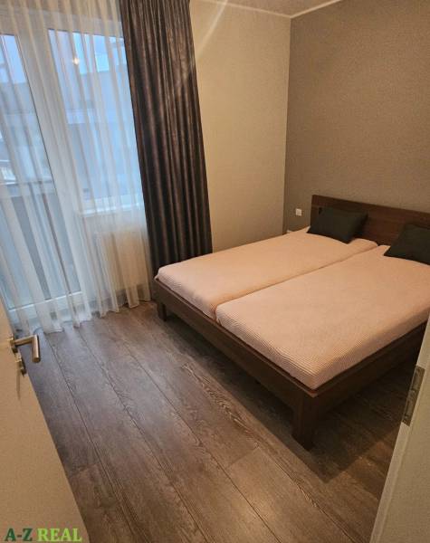 Bedroom in a 3-room apartment with wood-patterned flooring and a double bed.