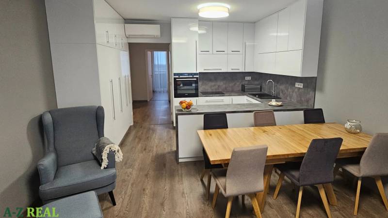A kitchen in a 3-room apartment with a wood-decor floor, a dining table, and light-colored furniture.