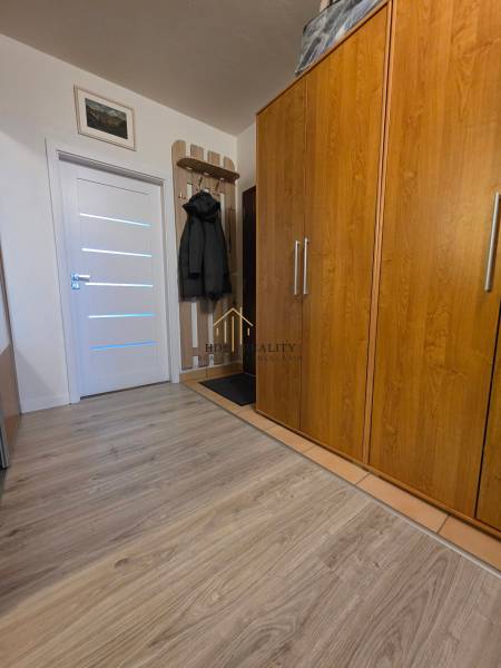 Interior of a 3-room apartment with a wooden decor floor, wardrobe, and coat rack.
