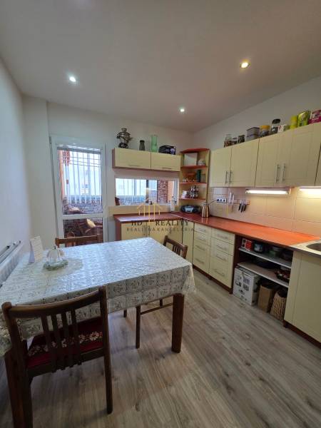 A kitchen in a 3-room apartment with a wooden decor floor and a dining table.