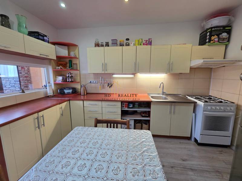 A kitchen in a 3-room apartment with a cream-colored kitchen unit and a wooden decor floor.