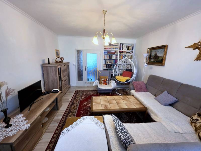 Living room in a three-room apartment with a wooden decor floor and bookshelves.