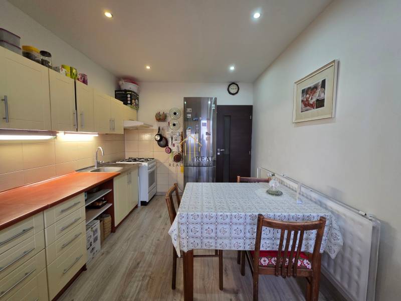 A kitchen in a 3-room apartment with a wooden decor floor and a dining table.