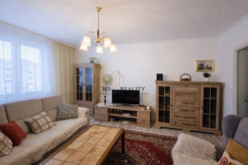 Living room in a three-room apartment with wooden decor and comfortable seating.