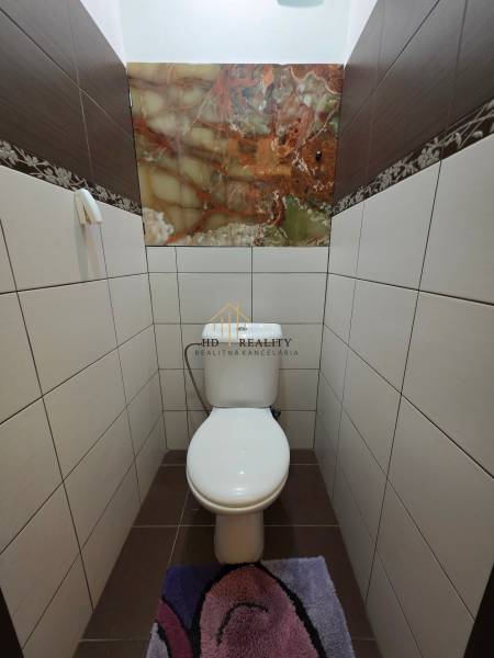 A toilet with light tiles and a decorative panel in a 3-room apartment.