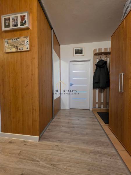 A hallway in a 3-room apartment with wooden decor and a coat rack wall.