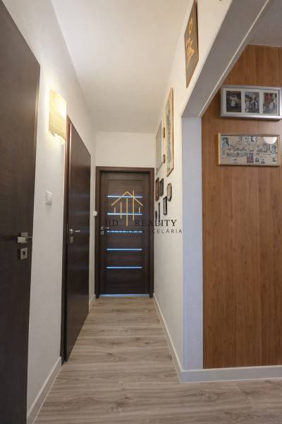 A hallway in a 3-room apartment with a wooden decor floor and dark doors.